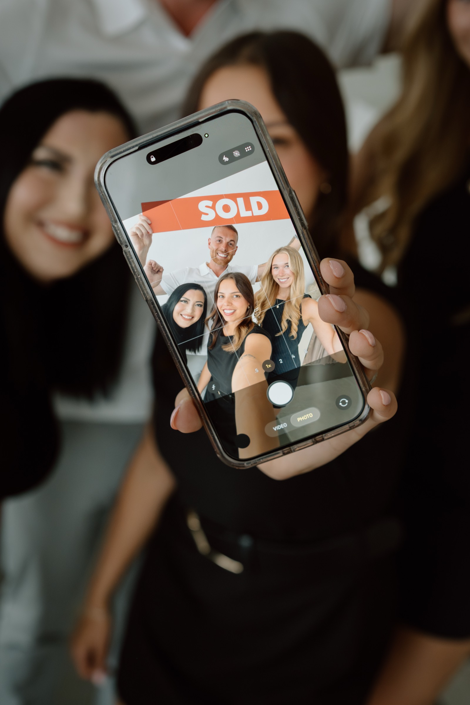 The Knight Group team showing a SOLD listing on a phone